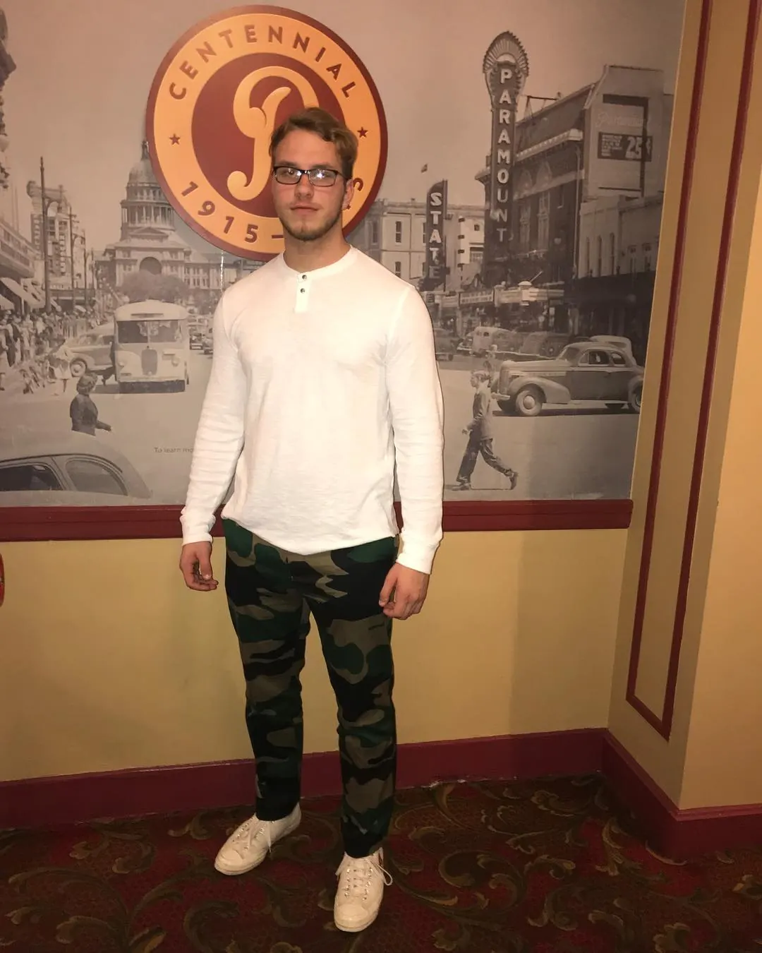 Tyler Henn standing by the centennial display at the Paramount Theatre in Austin, Texas