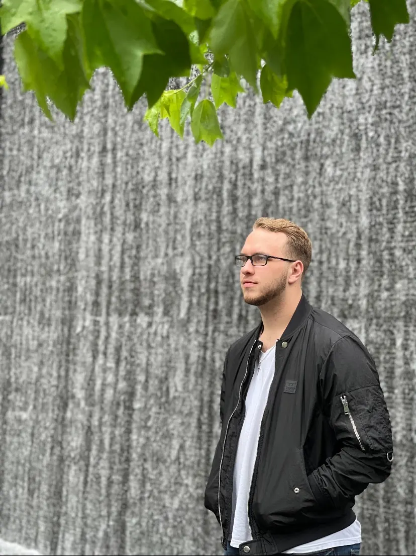 Tyler Henn posing beside a tall waterfall in downtown Nashville, Tennessee