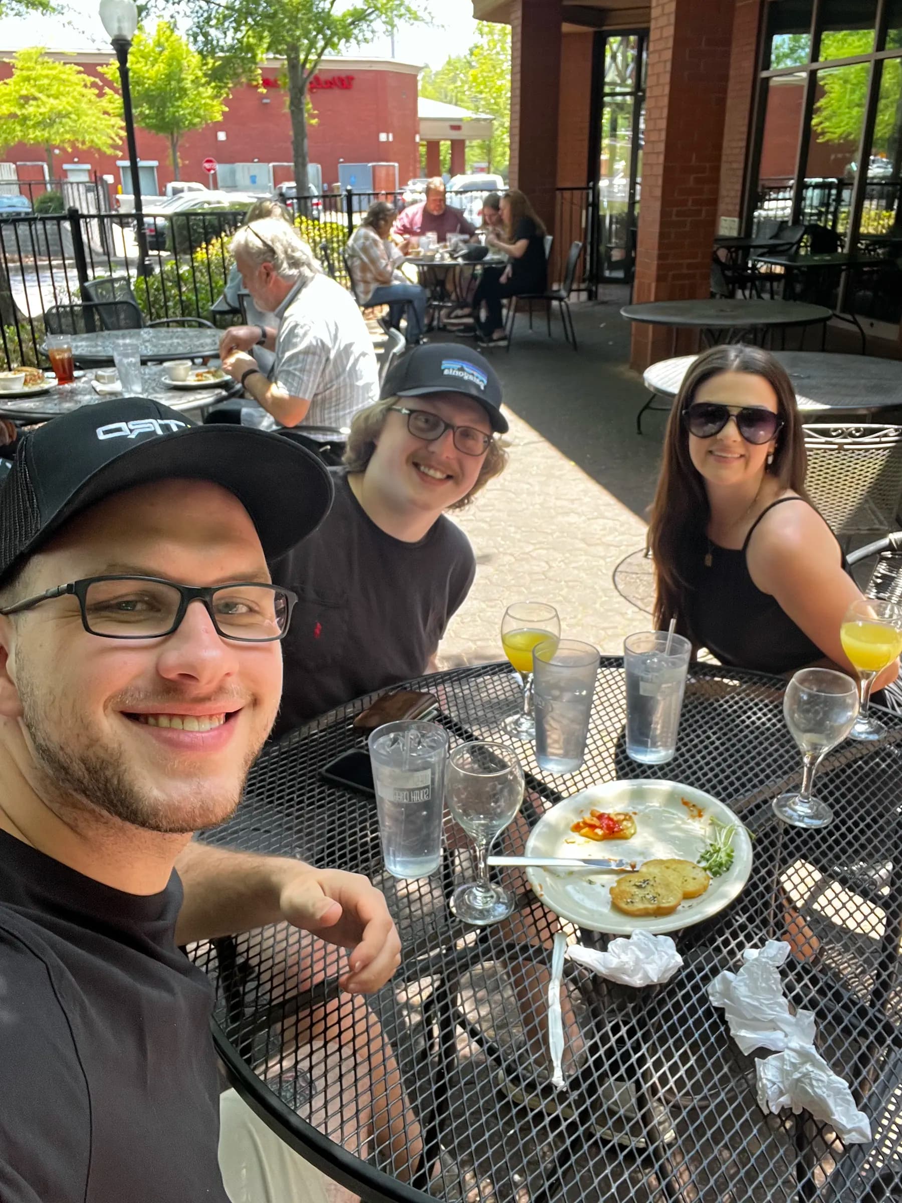 Tyler Henn seated at an outdoor restaurant table with two friends