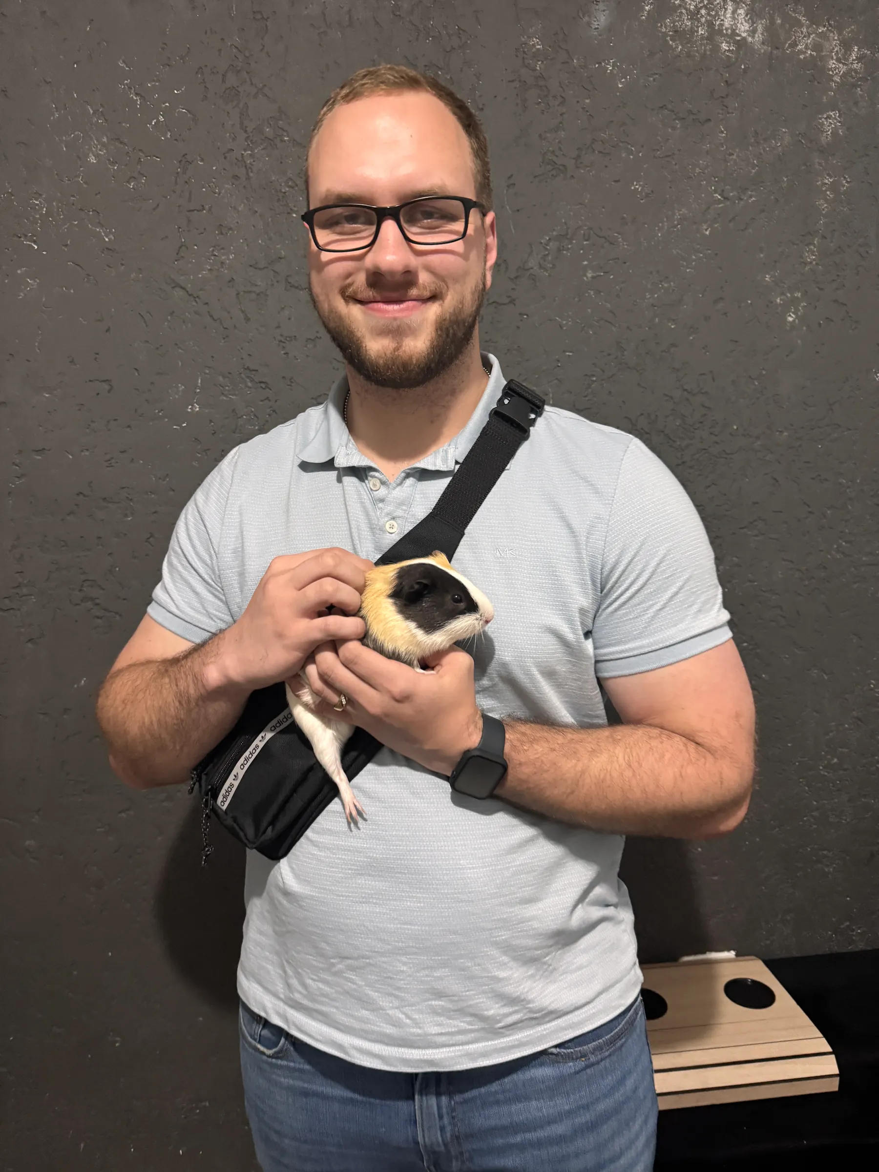 Tyler Henn smiling while holding and petting a guinea pig in São Paulo, Brazil