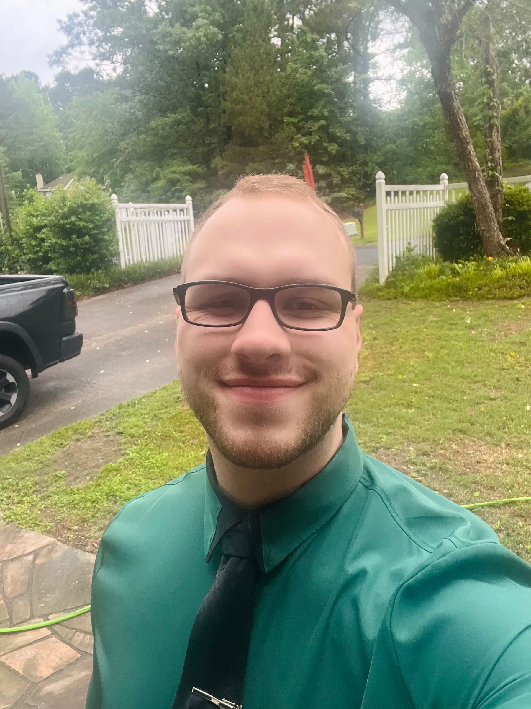 Tyler Henn taking an outdoor selfie in a green dress shirt and black tie