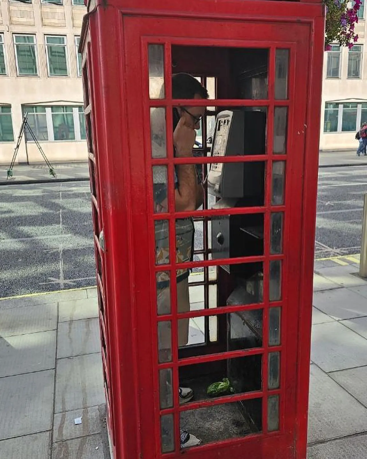 Tyler Henn using a red telephone box in London, England