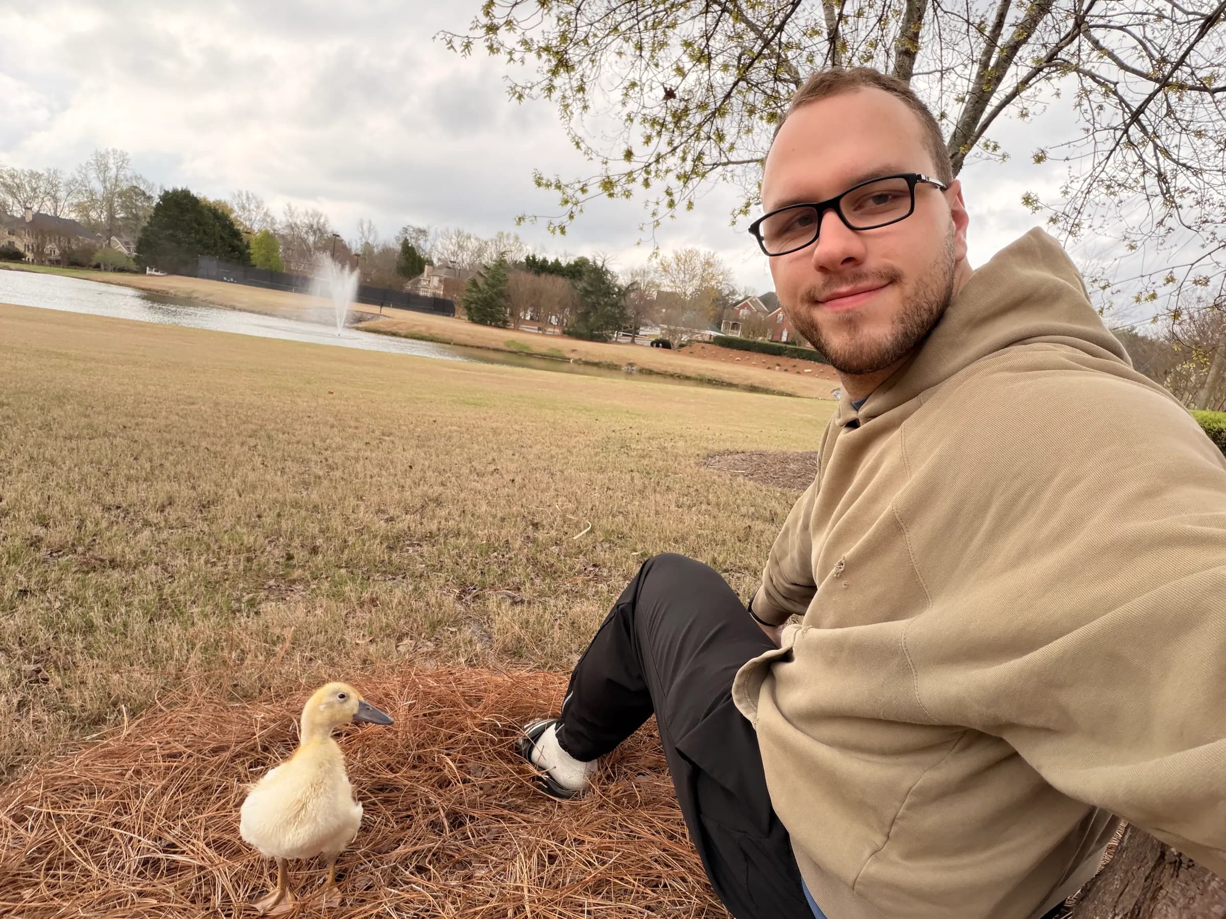 Tyler Henn taking a selfie beside a yellow duckling near a pond